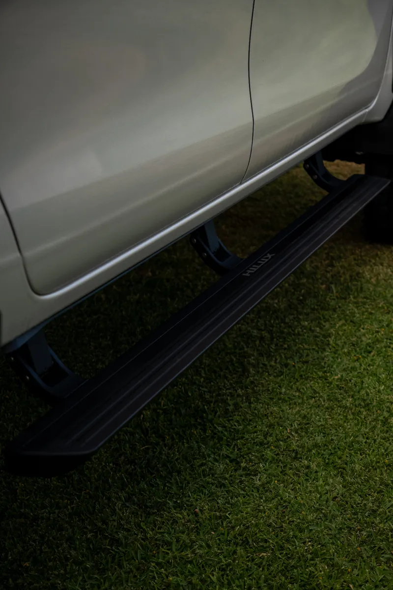 Black side step and mounting brackets beneath a white vehicle