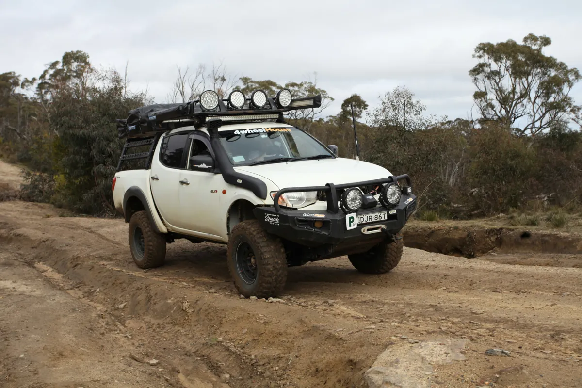 White touring 4x4 with roof-mounted driving lights and front protection